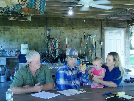 The Foos Family meet with NRCS District Conservationist  under a pavillion at their ranch..