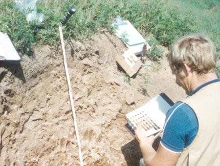 Vintage photo of a man holding a guide and conducting soil tests in a soil pit