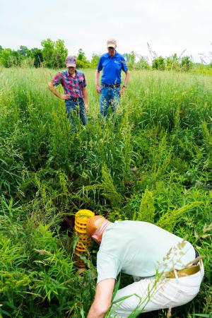 Tom Dykstra (front) shows Art Franke (back left), Indiana NRCS district conservationist for Steuben County, and Bill Lambert, Indiana NRCS northeast Area Easement Program Specialist, a tile riser inlet located on his 110-acre wetland reserve easement on June 7, 2022.