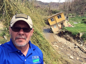 Luis Garcia seeking field staff in Utuado PR after Hurricane Maria - in front of destroyed house falling into the river.