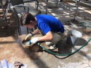 boy crouched on the ground with a hose in his hand