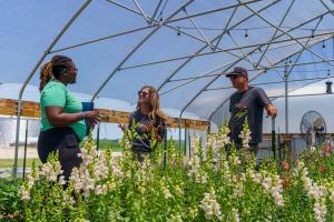 Sydney Lockett (left), district conservationist with USDA’s Natural Resources Conservation Service, talks with Carrie Kleiman, the owner of Floral Compass Flower Farm in Fountaintown, Indiana, and Nick Kleiman, about the farm’s high tunnel during a visit to the farm June 28, 2022.