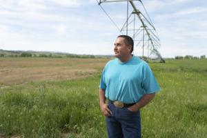 Man standing in a field in front of an irrigation system