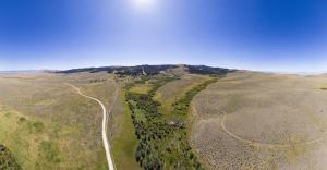 Aerial view of rangeland with partial brush management and bright blue skies above.