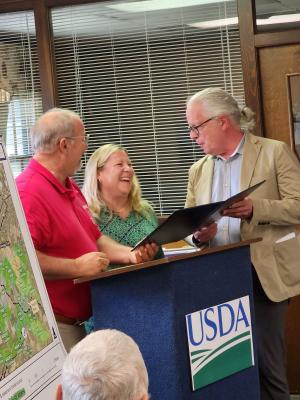 Randy Phiel and Kate Klunk present landowner Russell Williams with a proclimation