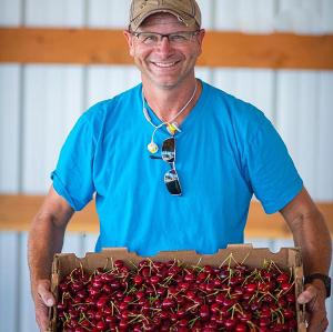 man holding box of cherries, smiling