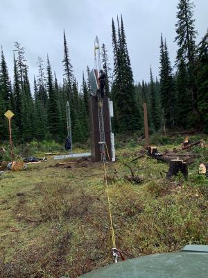 person standing on tower installing equipment in woods
