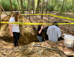 Students evaluate and classify soils in a test pit for 2024 RI Envirothon at Camp Hoffman.