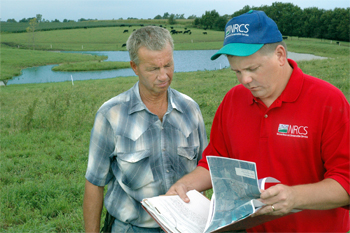 Louisa County Farmer Roger Edwards and NRCS District Conservationist Drew DeLang review Edwards� prescribed grazing conservation plan. Using Environmental Quality Incentives Program cost share, Edwards built fences and a cattle watering system that reduces erosion and makes his grazing land more efficient.