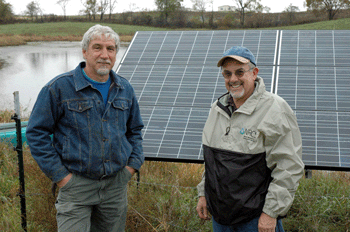 Thicke and NRCS District Conservationist David White stand next to a solar panel that powers a submersible pond pump which waters his 140 head of cattle.
